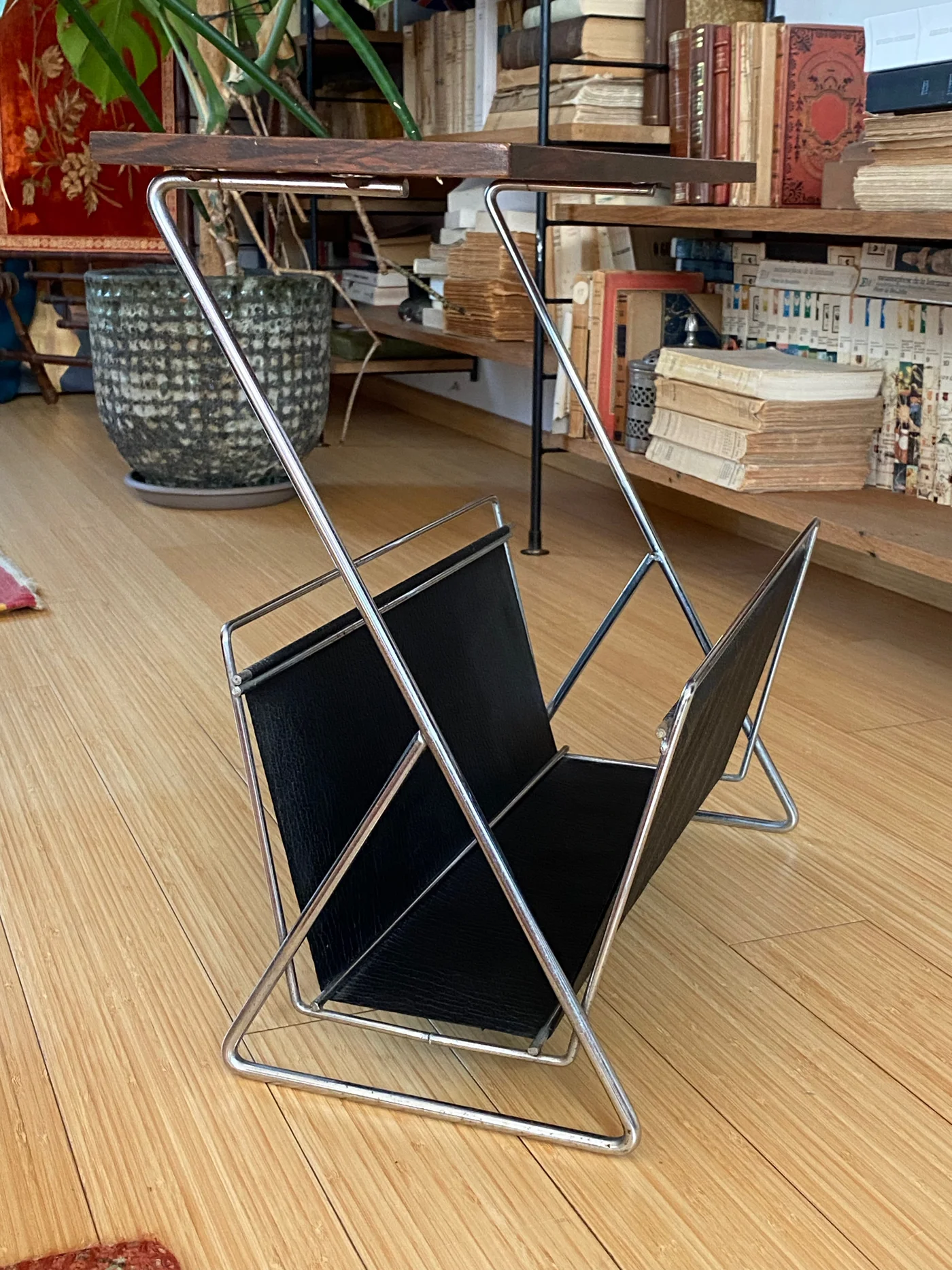 Porte-revues modèle années 1960-1970, avec structure tubulaire chromée, porte-revues en skaï noir, tablette supérieure en placage de bois foncé.